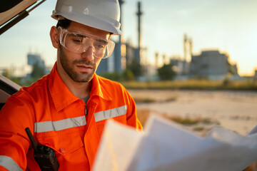 Engineer looking at refinery plans. - obrazy, fototapety, plakaty