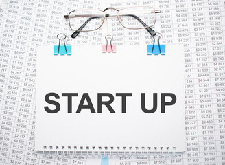 start up text written on paper with pen and glasses