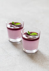 Panna Cotta black currant with berry sauce in a glass on a light background