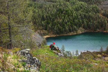 Man tourist is resting going on a hiking trip up the mountain against the background of a mountain lake