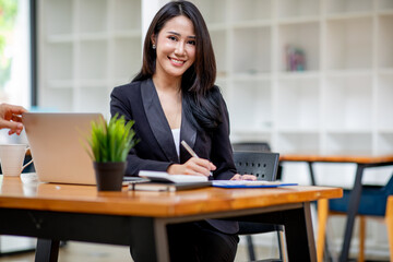 Portrait of Happy Young attractive business woman using digital laptop computer. do math finance on wooden desk, tax, accounting, report statistics and analytical research technology concept.