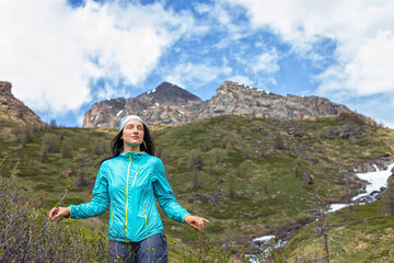Naklejka premium Woman is a happy beautiful tourist on a hike against the background of mountains and a mountain river