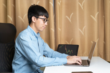 Happy young Asian man using laptop to study, learning on trading, investing, economic classes on...