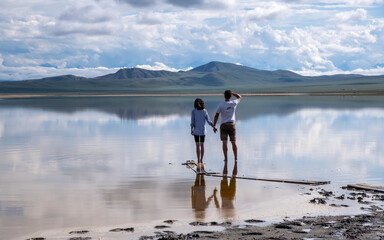 Fototapeta na wymiar a guy and a girl on the shore of a high mountain lake