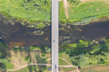 Aerial top down view of car driving over bridge. River flowing under bridge