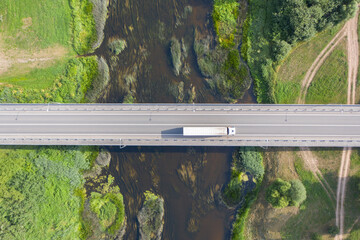 Aerial top down view of truck driving over bridge. River flowing under bridge © Abinieks