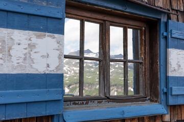 Fototapeta na wymiar Reflection of mountains in the window. Open traditional window shutters in Austria