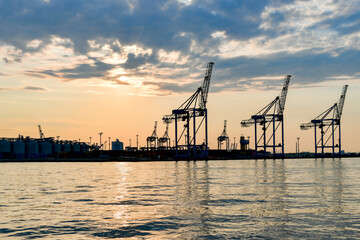 Fototapeta na wymiar Cranes and industrial equipment in the sea, cargo port. View from the sea.