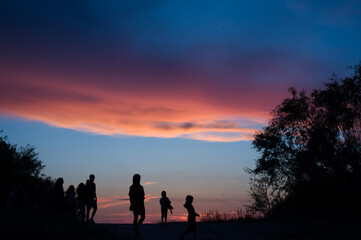 Fototapeta na wymiar Kontury sylwetki ludzi na tle zachodzącego barwnego nieba. 