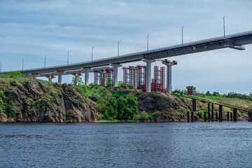 Construction of automobile bridge across the river. Industrial landscape.