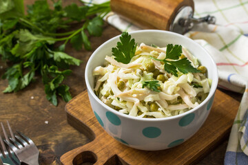 Salad with fresh cabbage, calamary, cucumber and green peas in a bowl on a rustic table.
