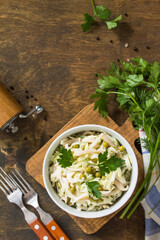 Salad with fresh cabbage, calamary, cucumber and green peas in a bowl on a rustic table. Top view flat lay background. Copy space.