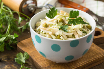 Salad with fresh cabbage, calamary, cucumber and green peas in a bowl on a rustic table.