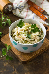 Salad with fresh cabbage, calamary, cucumber and green peas in a bowl on a rustic table. Copy space.