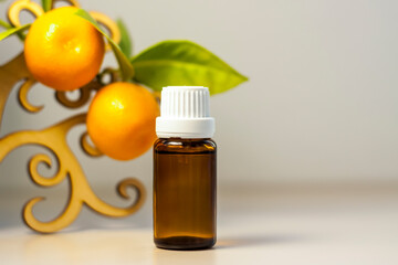 A bottle without a label with tangerine oil. Transparent glass bottle of brown color. A natural cosmetic product. Product banner. A place for text and design.