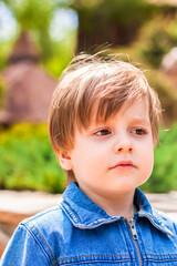 Close-up portrait of a small child smiling outdoors on a green background.