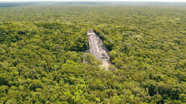 Aerial view of Ancient Mayan pyramid and Coba ruins in Mexico. Landscape panorama of Quintana Roo Peninsula from aboveL. Lush jungle on a sunny day, 4k UHD.