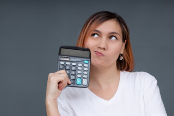 Portrait of a serious female accountant  holding a calculator on a gray background.