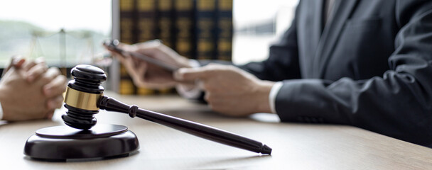 A small court judge's hammer is placed on the lawyer's table, the lawyer is advising the client to...