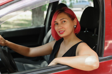 A young woman with pink hair is driving her car