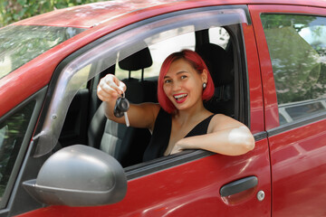 Young happy woman with pink hair showing the key of new car