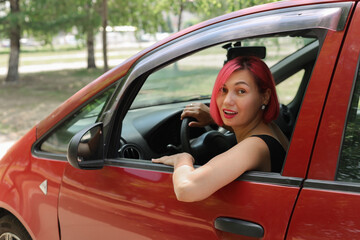 A young woman with pink hair is driving her car