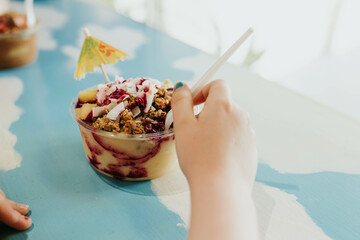 Child reaches for Acai and pineapple granola bowl