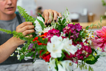 Crop female florist preparing a bunch of flowers