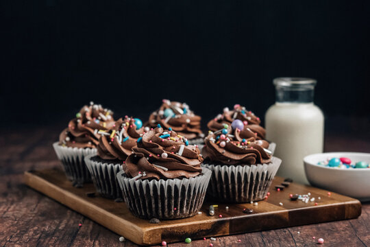 Chocolate cupcakes with sprinkles on wooden board