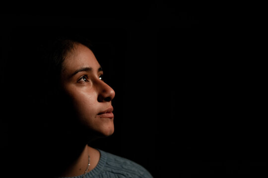 Portrait of Hispanic woman looking aside in the dark