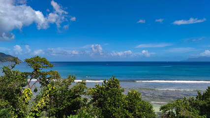 Calm Indian Ocean, green trees and bright sky, Seychelles