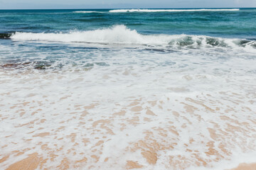 Crashing ocean waves hit along an Oahu beach shoreline