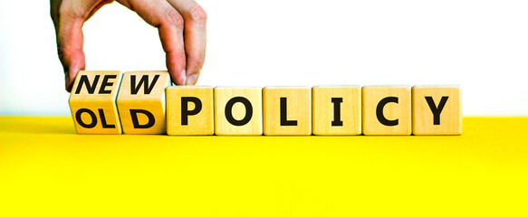 New or old policy symbol. Businessman turns wooden cubes and changes words 'old policy' to 'new policy'. Beautiful yellow table, white background. Business, old or new policy concept. Copy space.