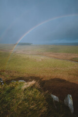 A double rainbow fills a dark blue sky along Hadrian's Wall in the UK.