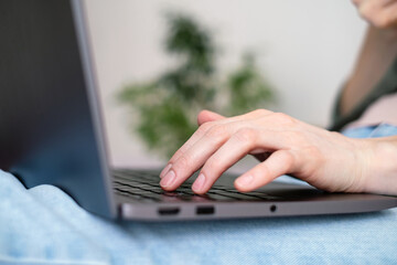 Close-up woman's fingers typing on a laptop.