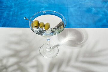 Cocktail glass with martini and olives by the pool. Soft drinks on a hot summer day day. Beach party in summer