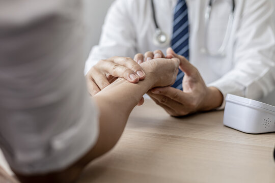 Close-up photo Doctor holding pulse on patient's wrist in the examination room, patient visits doctor due to discomfort. The concept of visiting a doctor when sick for a diagnosis.