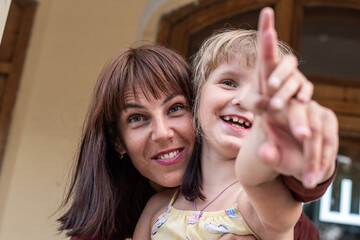 portrait of a mother and daughter in the summer in the city. a woman and a girl look into the distance and point with my finger. children and parents relations