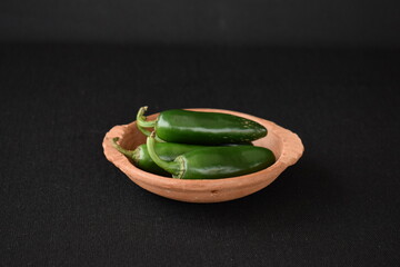 Hatching green New Mexico chilies in clay dish (hot peppers)