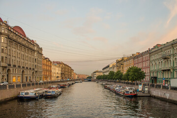 Saint PETERSBURG, RUSSIA-July, 15, 2021: Moika River embankment with moored boats with reflections in the water and historical buildings in the early summer morning