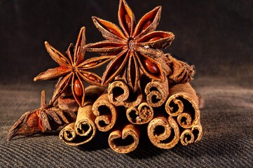 Obraz na płótnie Canvas Christmas baking spices, cinnamon sticks and anise stars for Christmas cake, cookies or mulled wine on a black background, macro photo
