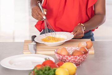 Close up of afro american woman using a whisk on some eggs: Cooking concept