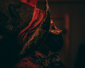 Selective focus of a person in a mysterious costume and venetian mask at a masquerade ball