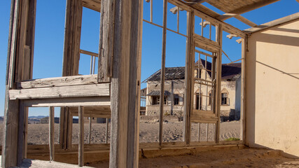 View through a wooden window frame of one of the neglected houses at the ghost town of Kolmanskop.