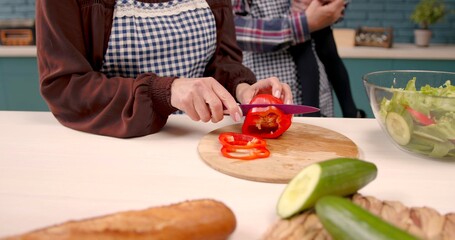 Hands of a woman who is cutting red bell pepper