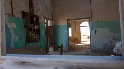 Inside of a sandfilled room at one of the houses framed by a windowframe at the ghost town of Kolmanskop, Namibia