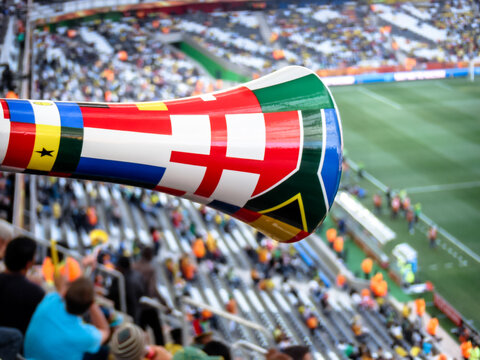 NELSPRUIT, SOUTH AFRICA - JUNE 25, 2010: A vuvuzela horn with world flags is shown over a football stadium