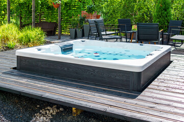 Large hot tub embedded in the backyard terrace. A sunny summer's day in the shelter of a green...
