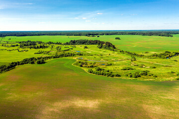 Top view of the winding river and summer fields with bushes