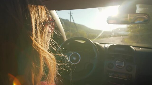 Woman driving convertible car at the sunset